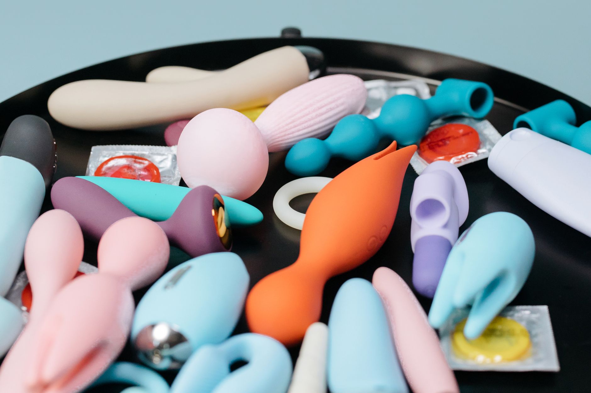 A person holding a basket of colorful vibrators including lemon-shaped toys