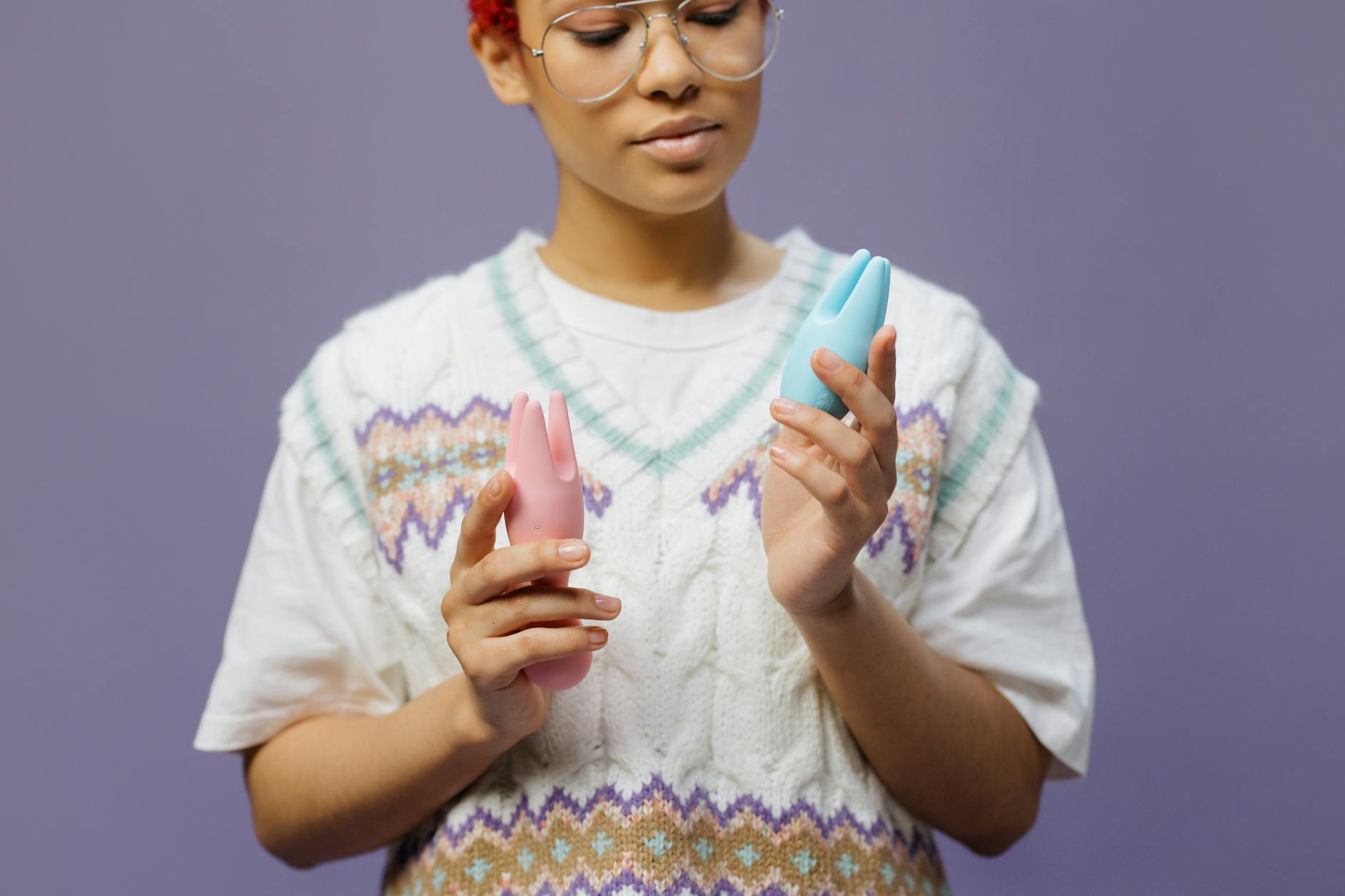 Woman holding colorful clitoral vibrators, exploring sensuality and pleasure options